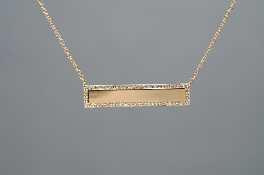 A Gold necklace with a rectangular landscape pendant 