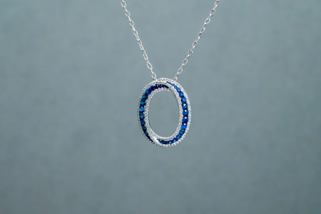 A necklace with an Oblong-shaped pendant filled with dark Blue gemstones 