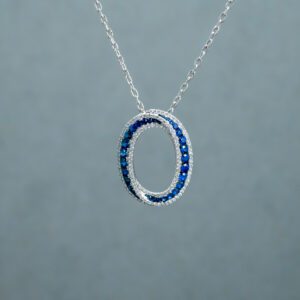 A necklace with an Oblong-shaped pendant filled with dark Blue gemstones 