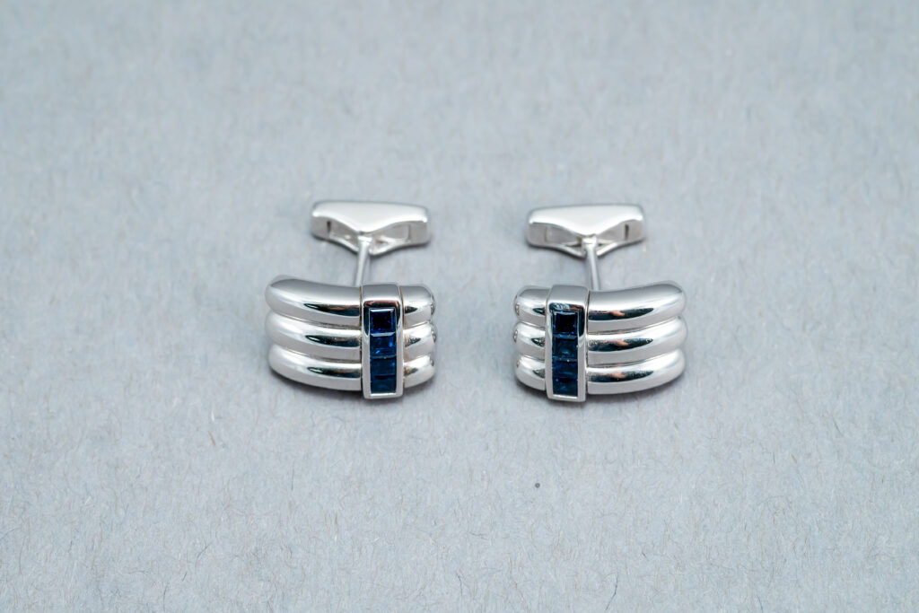 A pair of cufflinks with blue stones on them.