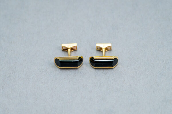 A pair of cufflinks with black stones on top.