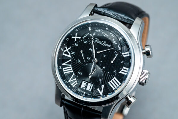 A black and silver watch on top of a leather strap.
