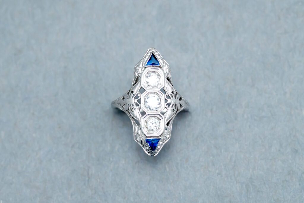 A diamond and sapphire ring is shown on top of a gray surface.