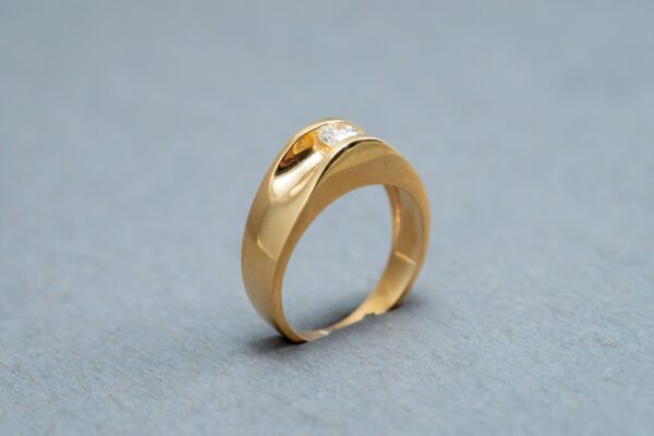 A gold ring with a diamond on it's side.