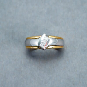 A silver and gold ring with a diamond on it.