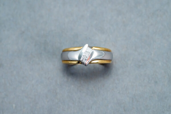 A silver and gold ring with a diamond on it.