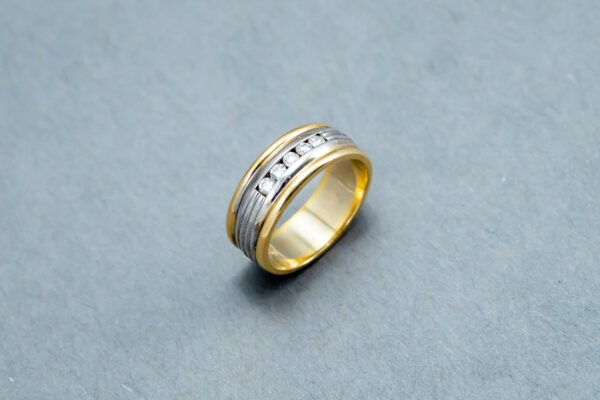 A gold and silver ring on top of a gray surface.
