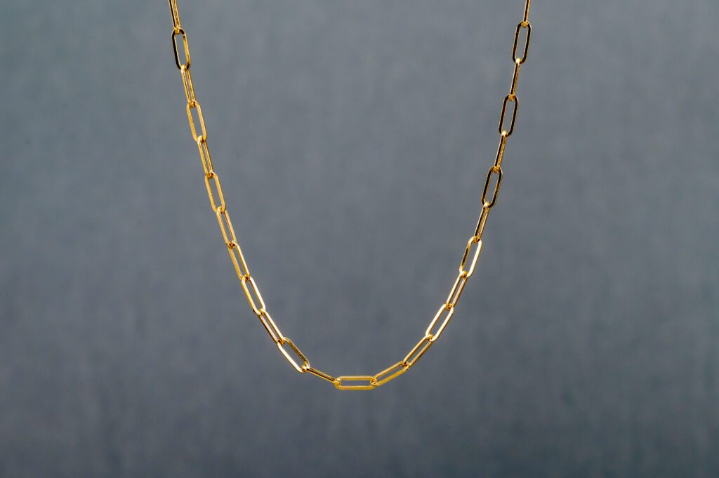 A close up of a chain necklace on a gray background