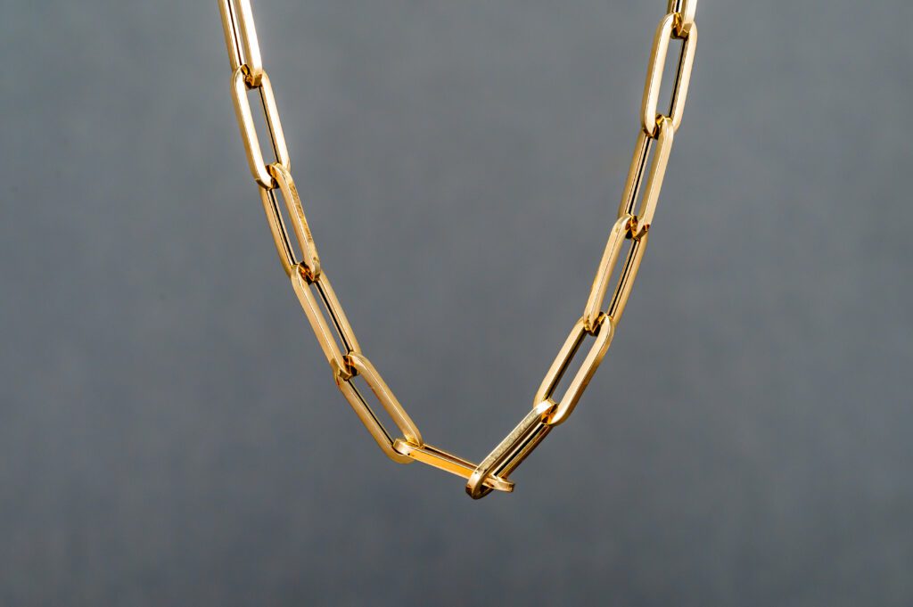A gold chain necklace with a large link.