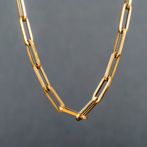 A gold chain necklace with a large link.