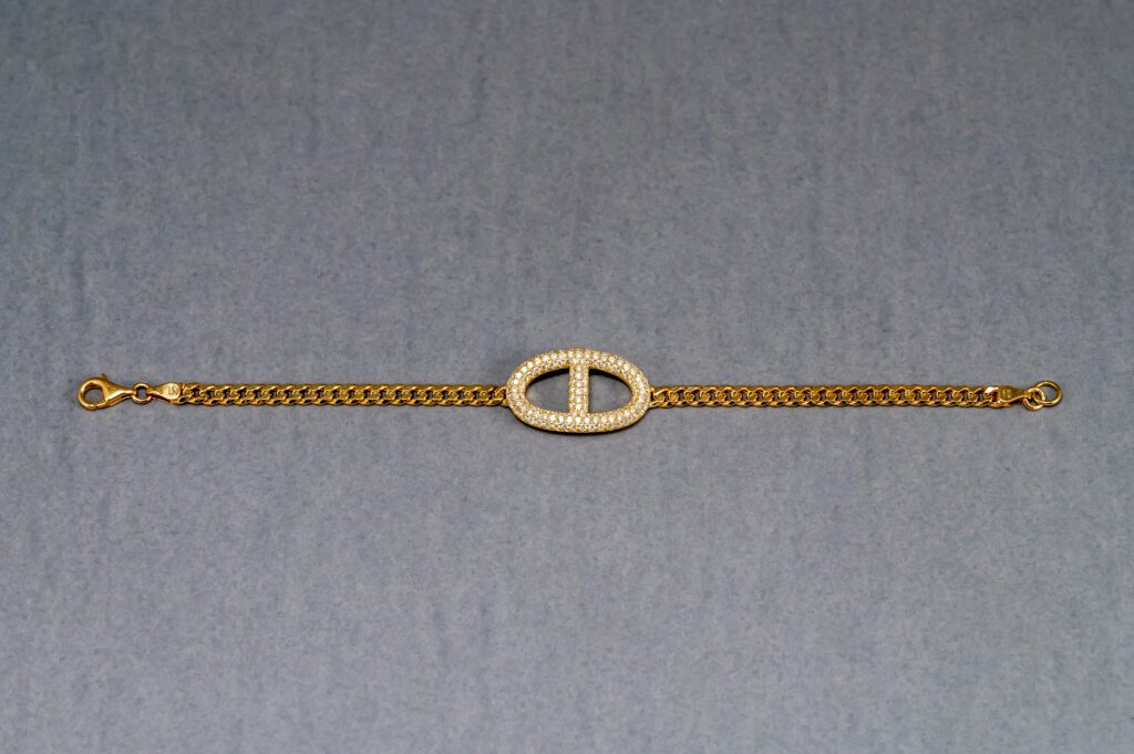 A gold chain with a small white circle on it.
