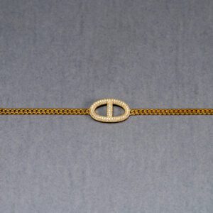 A gold chain with a small white circle on it.