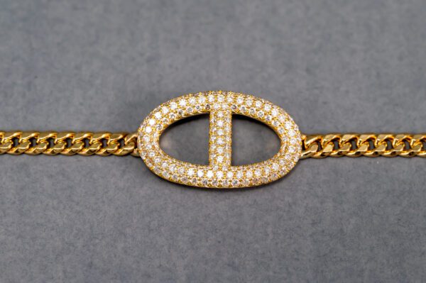 A gold chain with a diamond and t shaped bracelet.