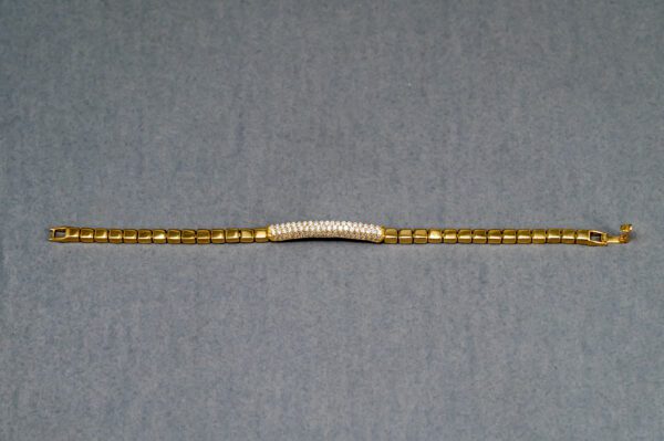 A gold chain with a white bead and a small diamond bar.