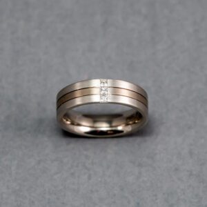 A silver ring with two lines and one diamond.