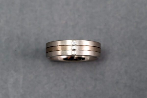 A silver and gold ring with three lines on it.