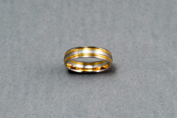 A gold and silver ring on top of a gray surface.