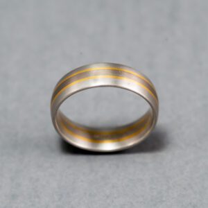 A silver ring with gold stripes on it.