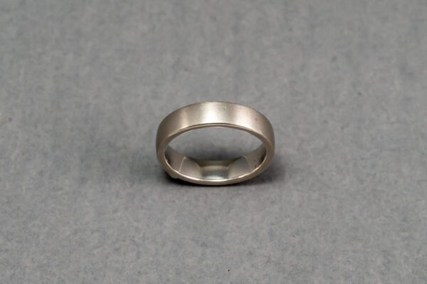 A silver ring is shown on top of a gray surface.