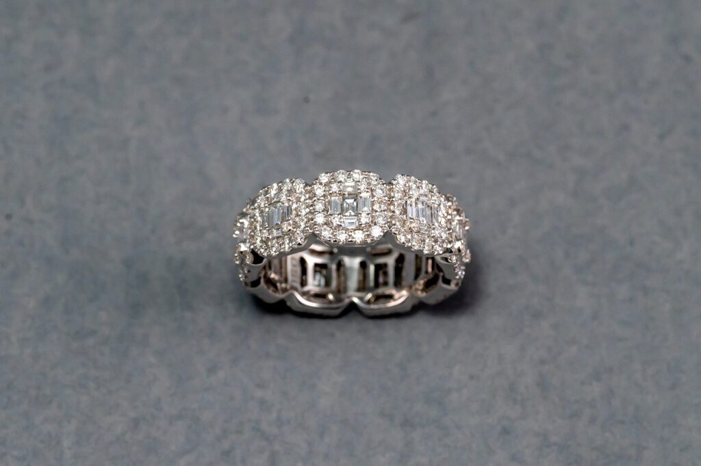 A diamond ring is shown on top of a gray surface.