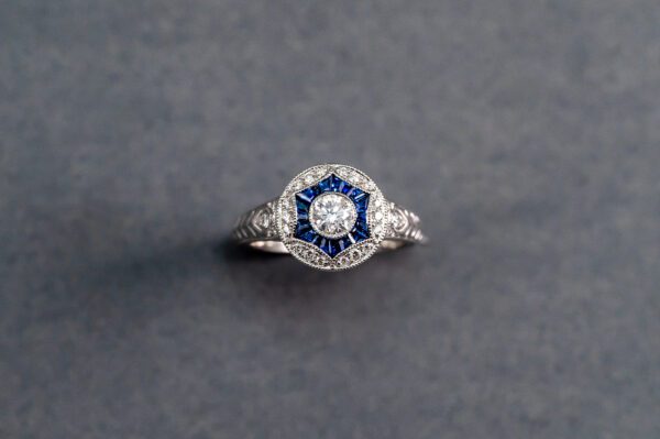 A diamond and blue stone ring on a gray background