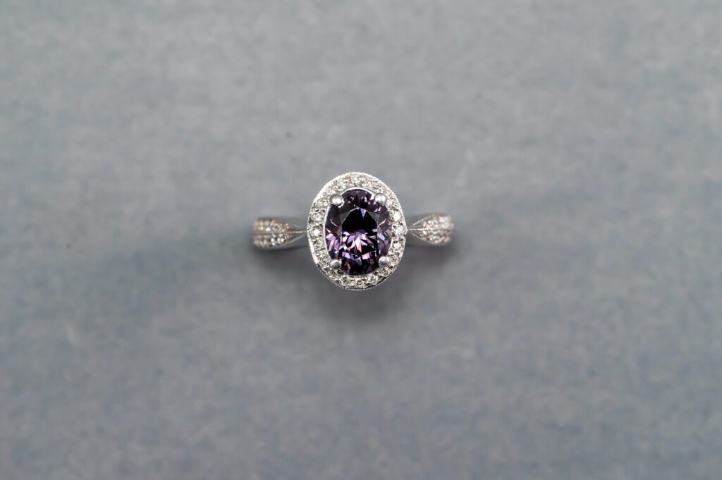 A purple diamond ring is shown on top of a gray background.