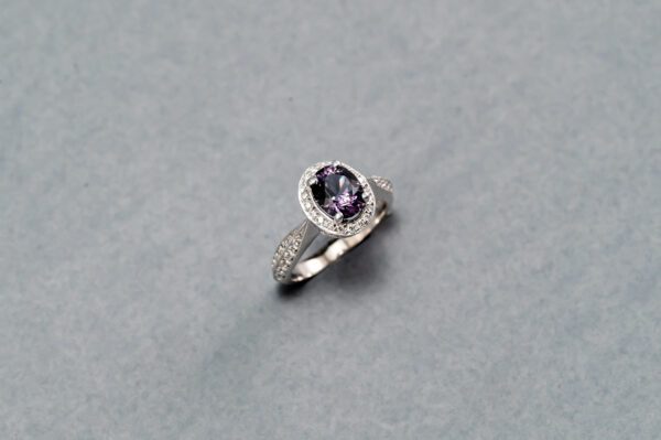 A silver ring with a purple stone on it.