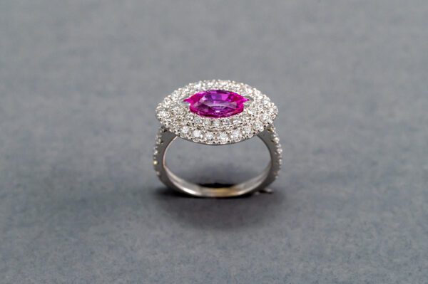 A pink and white diamond ring on top of a gray surface.