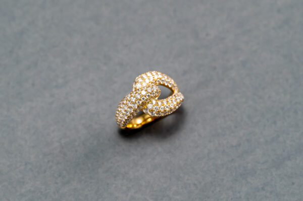 A gold ring with diamonds on top of a gray surface.