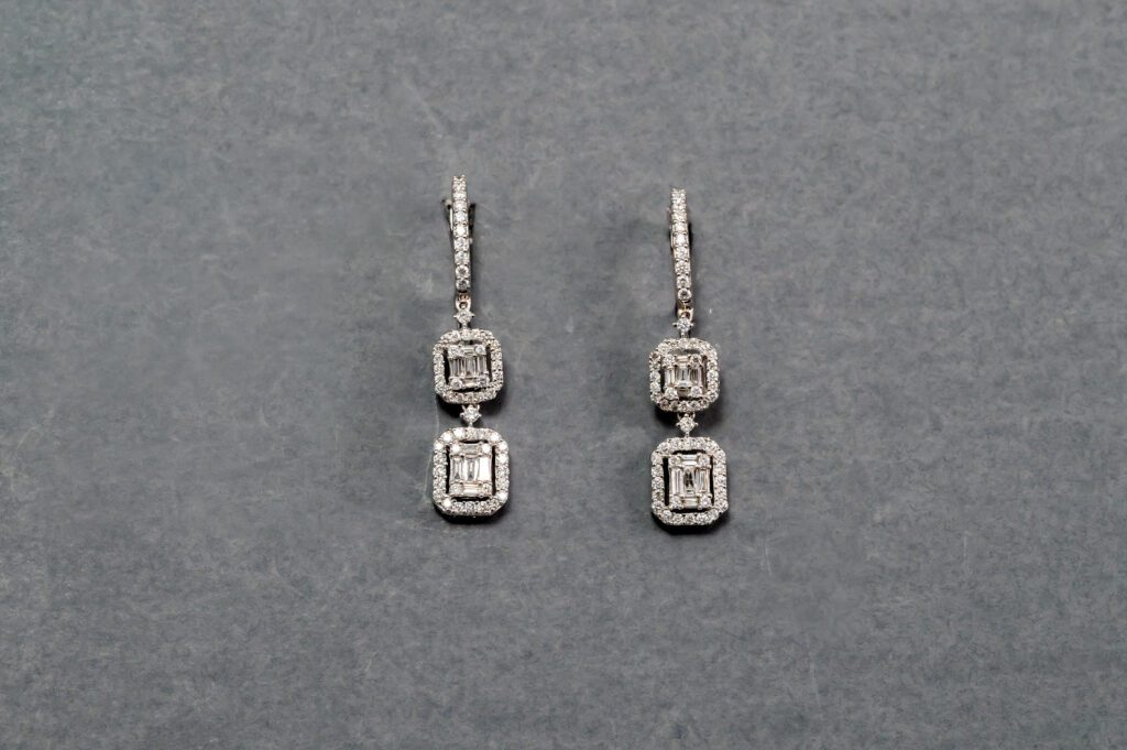 A pair of earrings with two square shaped diamonds.