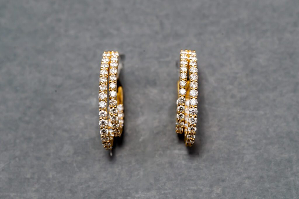 A pair of gold earrings with diamonds on top.