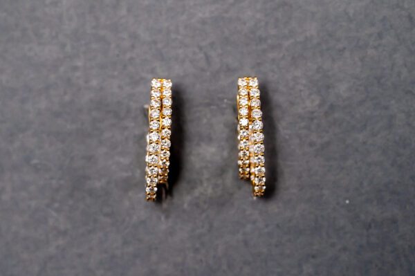 A pair of gold earrings with white stones.