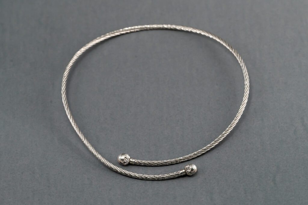 A silver necklace with two small balls on it.