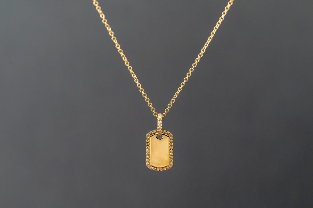 A gold chain with a small dog tag on it.