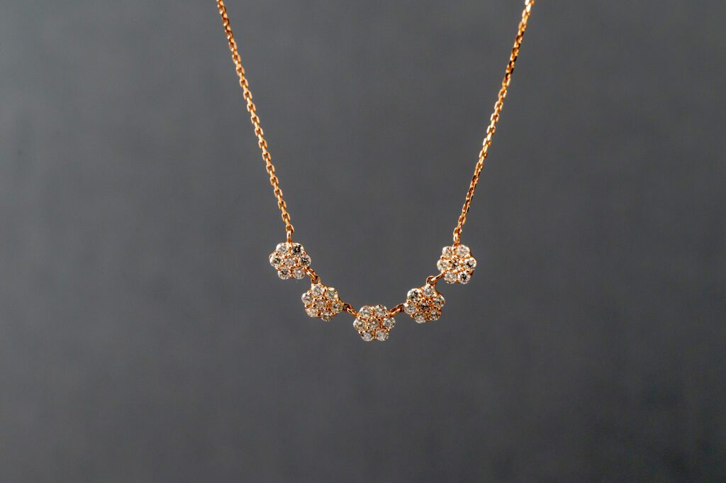 A gold necklace with five flowers on it.