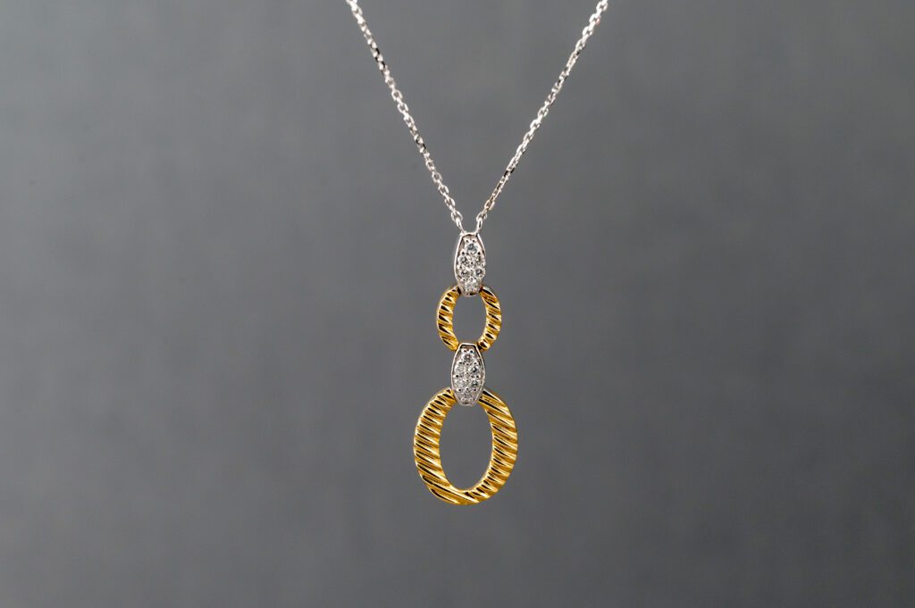 A necklace with two gold and diamond rings on it.