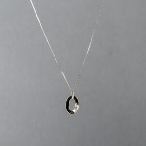 A silver necklace with an oval shaped pendant.