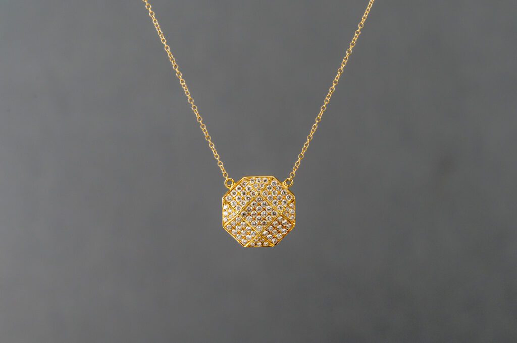 A gold necklace with a diamond in the middle of it.