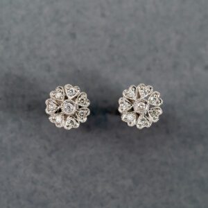 A pair of diamond earrings on a gray surface.