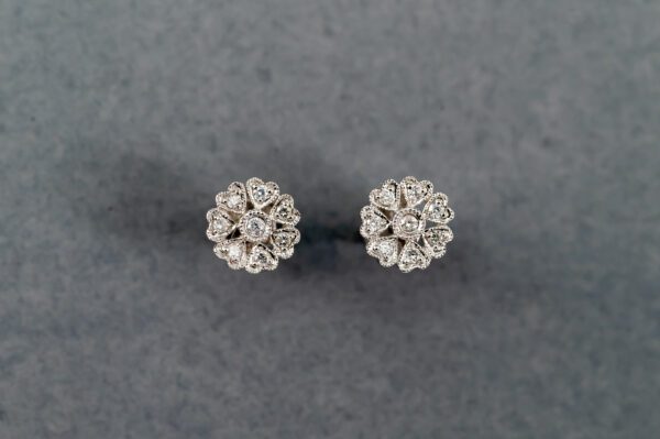 A pair of diamond earrings on a gray surface.