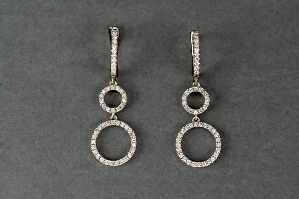 A pair of diamond earrings with two circles hanging from them.