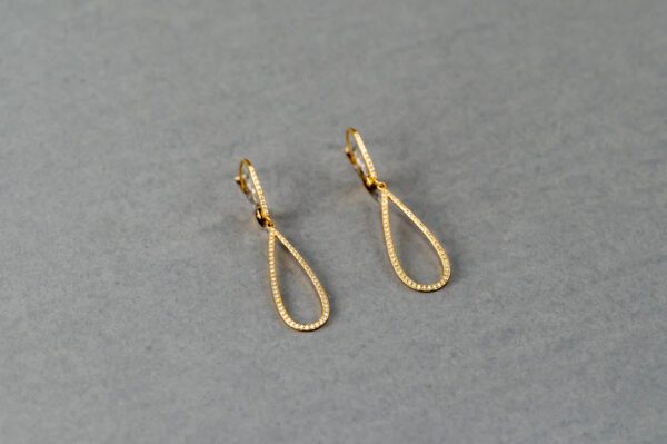 A pair of gold earrings on top of a table.
