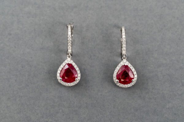 A pair of earrings with red and white stones.