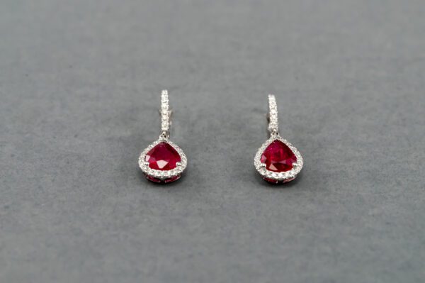 A pair of earrings with red stones and white diamonds.