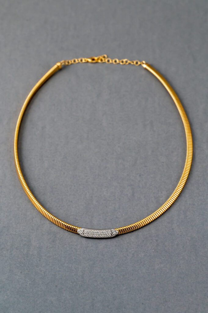 A gold necklace with a diamond bar on it.