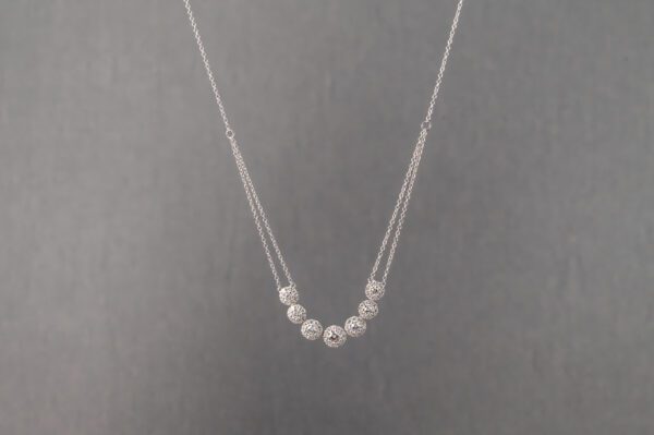 A silver necklace with seven beads on it.