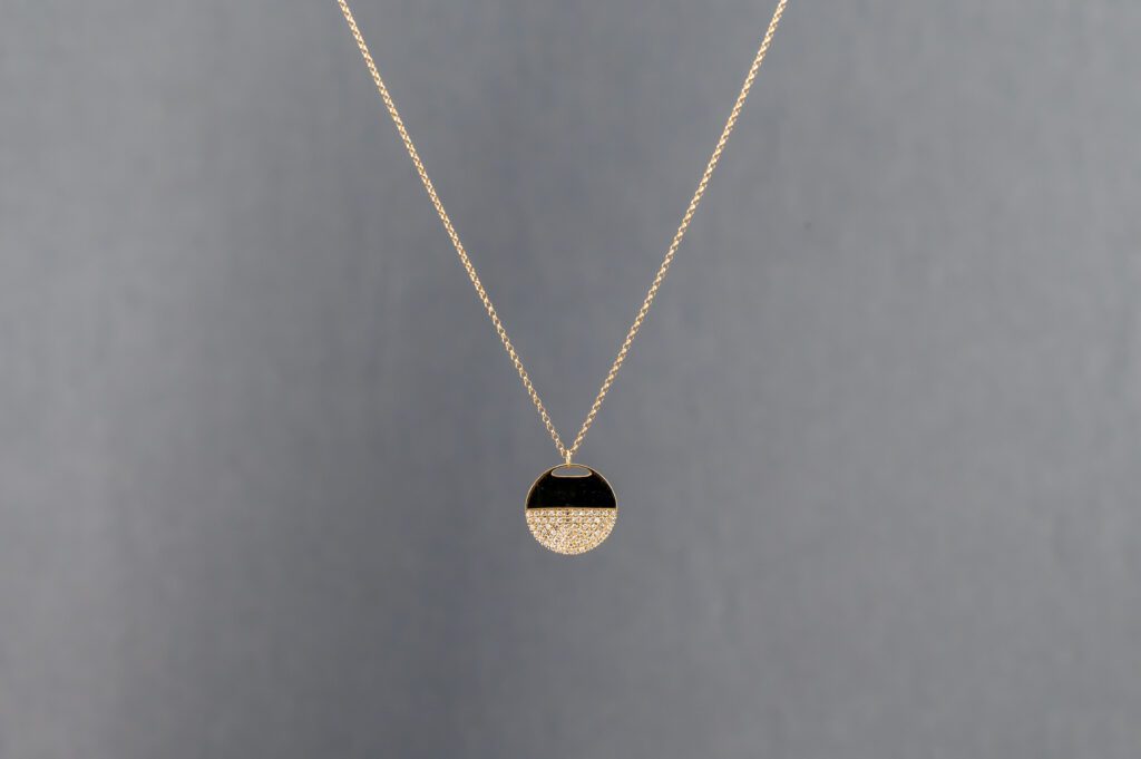 A gold necklace with a black and white pendant.