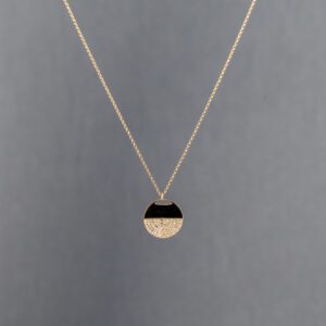 A gold necklace with a black and white pendant.