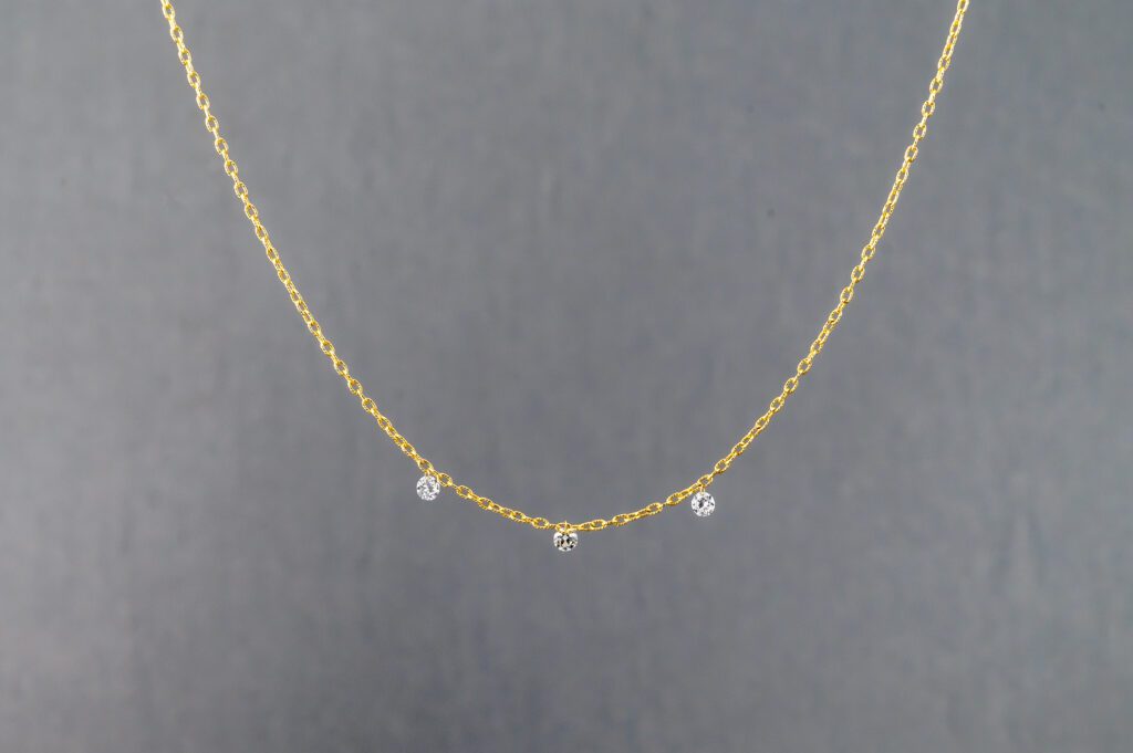 A gold necklace with three small diamonds on it.