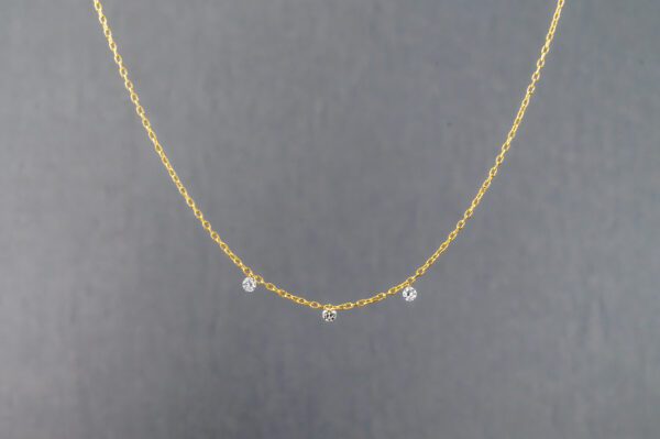 A gold necklace with three small diamonds on it.